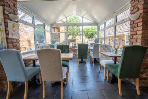 a dining room with tables and chairs and windows at Harmony House Boutique B&B in Stillingfleet