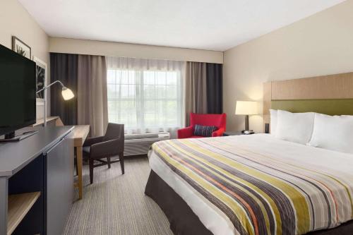 um quarto de hotel com uma cama, uma secretária e uma televisão em Country Inn & Suites by Radisson, Jackson-Airport, MS em Pearl