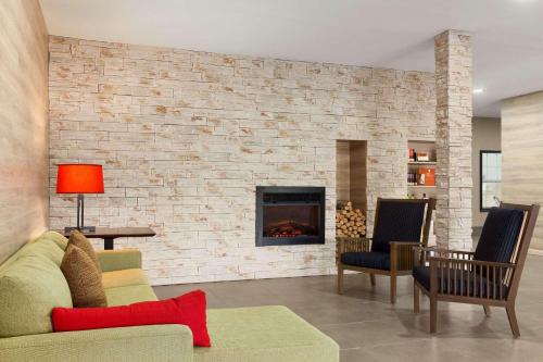 a living room with a brick wall with a fireplace at Country Inn & Suites by Radisson, Jackson-Airport, MS in Pearl