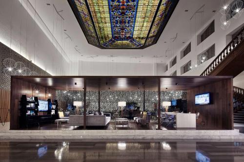 a lobby with a large stained glass ceiling and a room with couches at Wyndham Monterrey Ambassador Centro in Monterrey