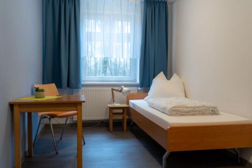 a room with a bed and a desk and a window at Gästehaus am Oberlausitzer Dreieck in Bertsdorf