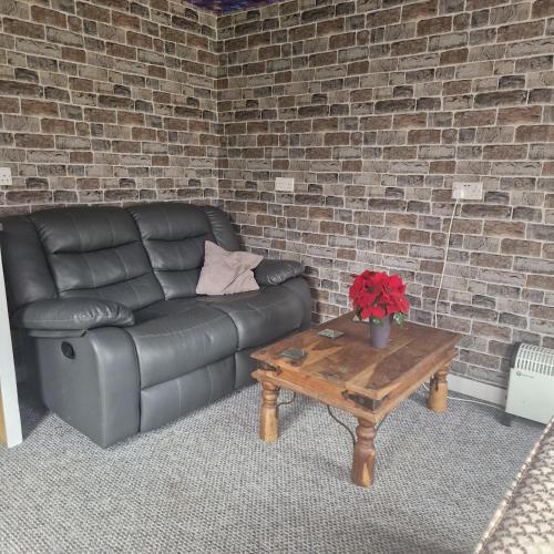 uma sala de estar com um sofá de couro e uma mesa de centro em Guest house with appliances em Brixworth