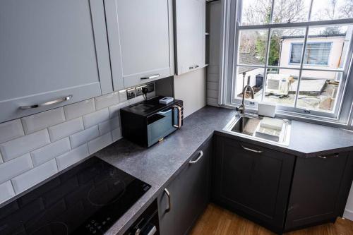 een keuken met zwarte kasten, een wastafel en een raam bij Studio Coastal Escape Apartment 2 in Christchurch