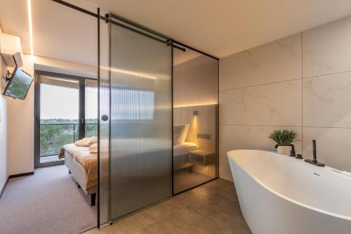 a bathroom with a bath tub and a bedroom at Hotel Jurmala Spa in Jūrmala