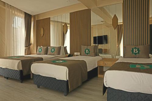 イスタンブールにあるビジム ホテルのベッド3台と鏡が備わるホテルルーム