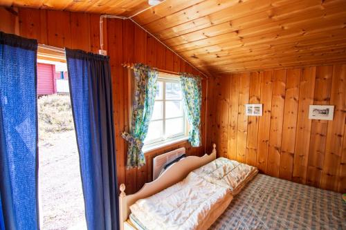 una mujer acostada en una cama en una habitación de madera en Gopshusgården - Rum & Stugor en Mora