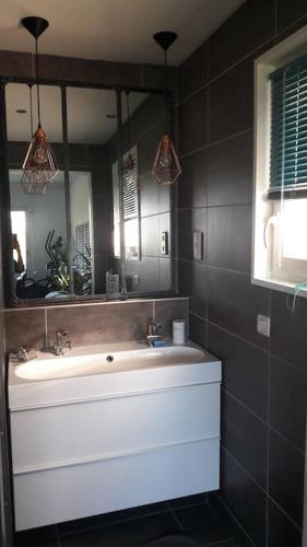 une salle de bain avec un lavabo blanc et un miroir dans l'établissement Maison lumineuse & chaleureuse, à Saint-Romain-au-Mont-dʼOr