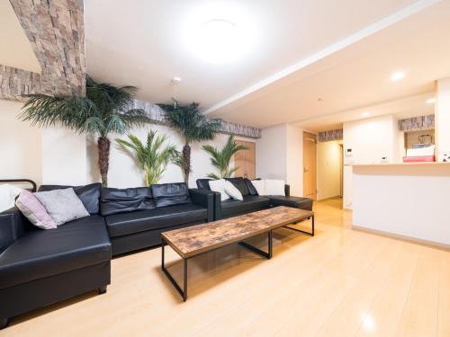 a living room with a black couch and palm trees at Shinjuku, 1min walk from Kagurazaka Sta,80sqm,Family-Friendly, in Tokyo