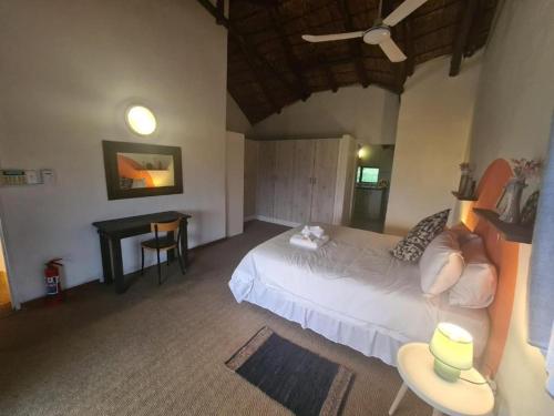 a bedroom with a white bed and a desk at Villa Paradiso in Hartbeespoort