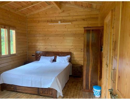 Forest View farmhouse stay, Nainital في ناينيتال: غرفة نوم بسرير في كابينة خشبية