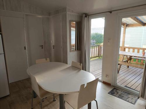a white table and chairs in a room with a deck at Mobilhome Caraibes in Oye-Plage