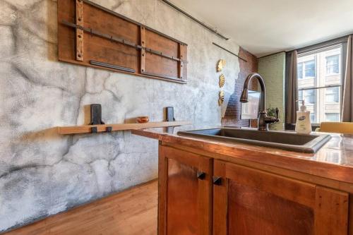 a kitchen with a sink and a stone wall at Chic Downtown Retreat - Rooftop Oasis in Bangor