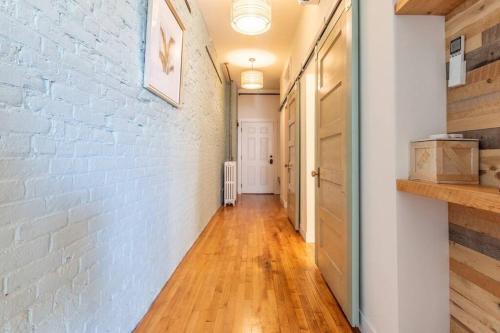 a hallway with a white brick wall and a wooden floor at Chic Downtown Retreat - Rooftop Oasis in Bangor