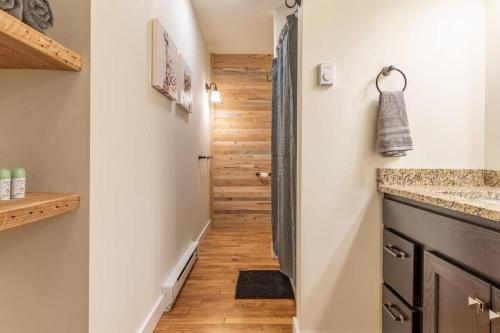 a hallway with a staircase leading up to a bathroom with wood floors at Chic Downtown Retreat - Rooftop Oasis in Bangor