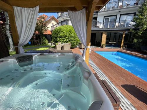 a hot tub on a deck next to a swimming pool at Villa Verdi Pleasure & Spa in Łeba