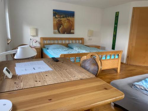 a room with two beds and a wooden table at Ferienzimmer Oelhaf Zimmer in Weiss Self Check-In mit Key-Tresore in Wilhelmsdorf