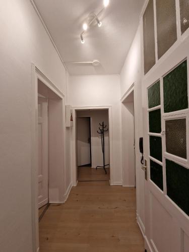 un pasillo con paredes blancas y un pasillo con puerta en Wohnen in Delstern wie im Urlaub en Hagen