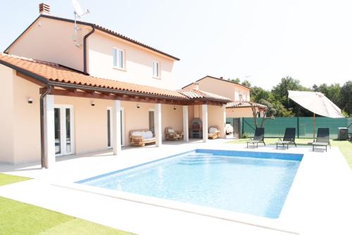a villa with a swimming pool in front of a house at Neue VILLA ROSE Fazana in Pula