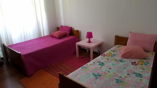 a bedroom with two beds and a pink lamp on a table at Quinta da Lage in Barcelos
