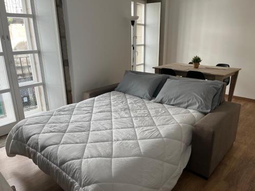 een bed in een slaapkamer met een tafel en ramen bij Apartamento con encanto in Santiago de Compostela