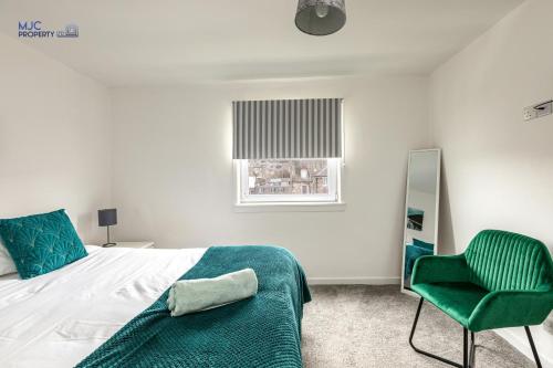 a bedroom with a bed and a green chair at Town Centre Apartment in Hawick