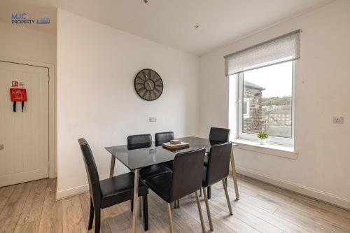 a dining room with a table and chairs and a clock at Town Centre Apartment in Hawick