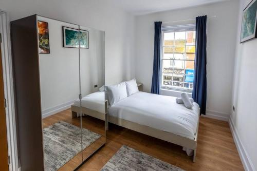 Dormitorio pequeño con cama y espejo en 1BR Towncenter Serenity - A Coastal Apartment 1, en Christchurch