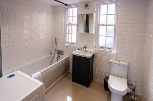 a bathroom with a tub and a toilet and a sink at 1BR Towncenter Serenity - A Coastal Apartment 1 in Christchurch