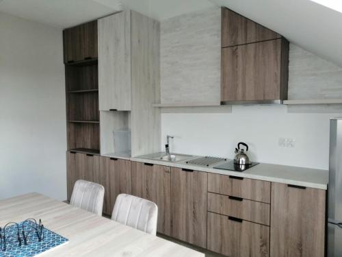 uma cozinha com armários de madeira e um lavatório em Rybitwy Residence em Mielno