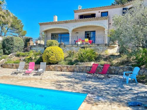 uma casa com cadeiras e uma piscina em frente em Magnifique villa avec Piscine Vue mer em Sanary-sur-Mer