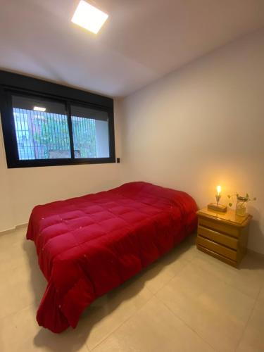 1 cama grande de color rojo en un dormitorio con ventana en Departamento Rosario en Rosario