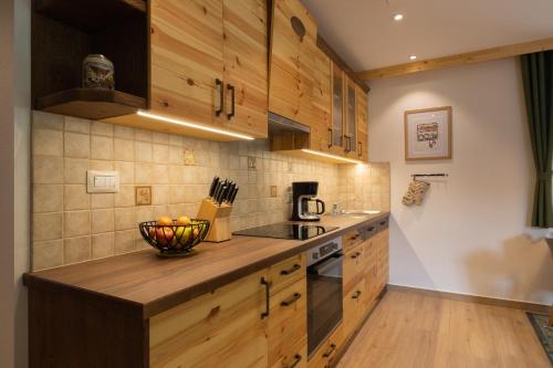 a kitchen with wooden cabinets and a bowl of fruit on a counter at PRIVILLAGE Stare - B&B in Bohinj
