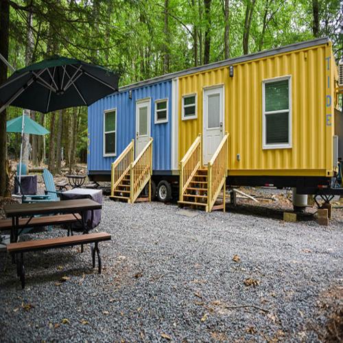 a yellow and blue trailer with a table and an umbrella at Camptel Poconos in Albrightsville