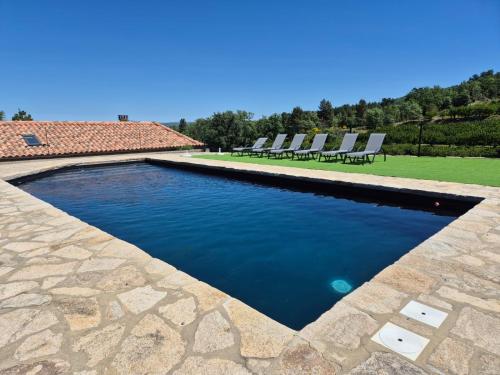 a swimming pool with chairs in a yard at Quinta do Limite - Casa do Camponês in Covilhã