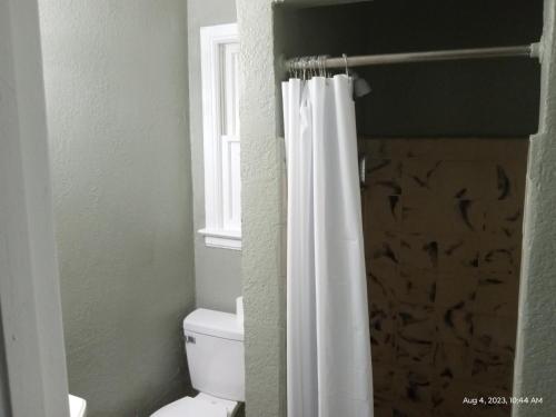 a bathroom with a toilet and a shower curtain at Homes -N - Courts in Sanford