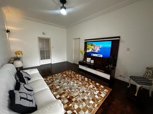a living room with a white couch and a flat screen tv at Casa Aconchegante-Rio de janeiro in Rio de Janeiro
