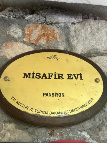 a metal sign on the side of a stone wall at Misafir Evi in Kayakoy
