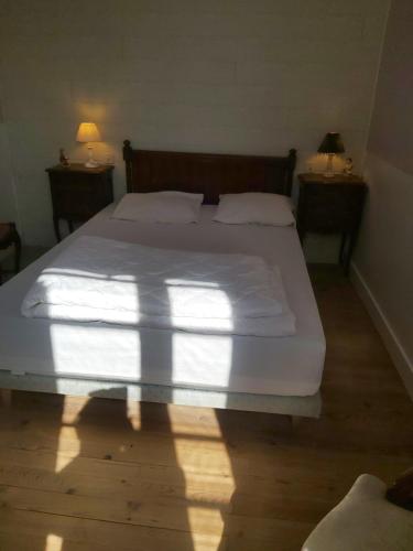 a bedroom with a large white bed with two night stands at Maison Quebec in Bernières-sur-Mer