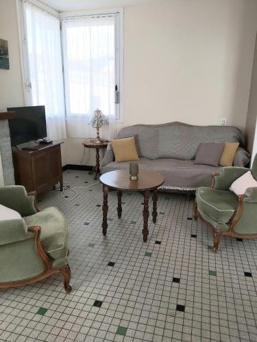 un salon avec un canapé, une table et des chaises dans l'établissement Maison Quebec, à Bernières-sur-Mer