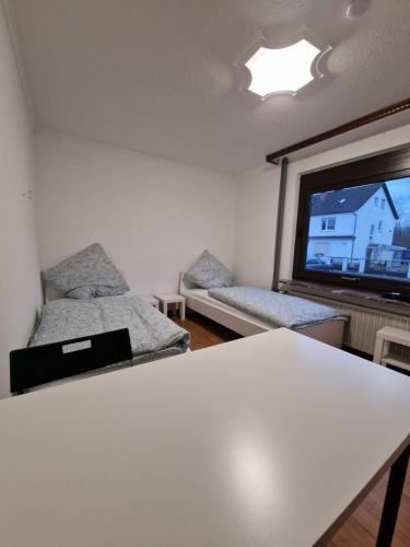 a room with two beds and a table and a window at AR Living Rüsselsheim Paul-Hessemer-Str in Falkenberg