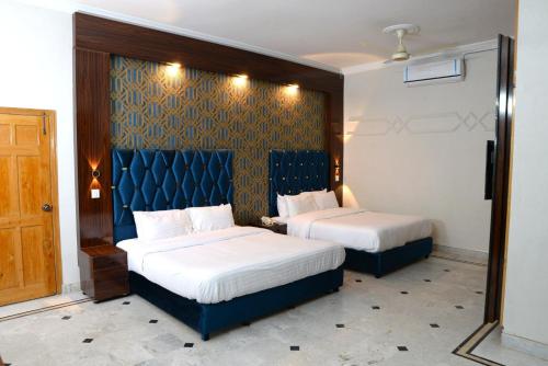 two beds in a room with a blue headboard at Pyramid International Guest House in Islamabad