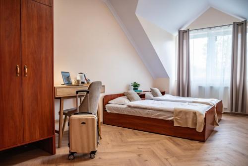 Un dormitorio con una cama y un escritorio con una maleta. en Ośrodek Wczasowy Alicja, en Ustka