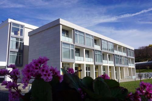 an office building with purple flowers in front of it at Hotel Pedras Salgadas in Pedras Salgadas