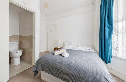 a white bedroom with a bed and a toilet at Calderon Road in London