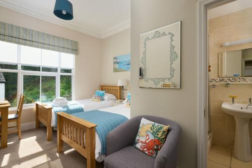 1 dormitorio con cama, silla y lavamanos en Epchris House, en Ilfracombe