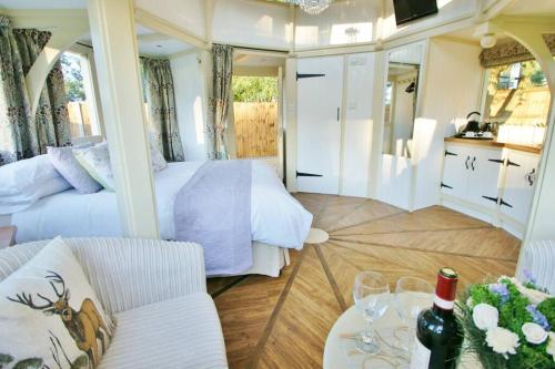 ノリッジにあるThe Folly - one off luxury Glamping accommodationのベッドとソファとテーブルのある部屋
