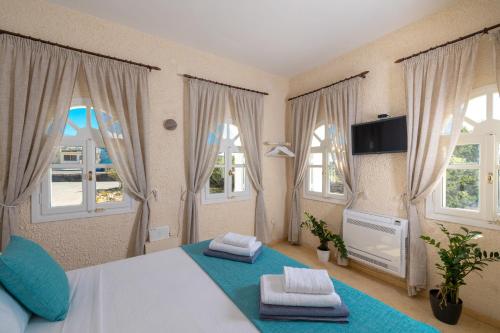 a bedroom with a bed and windows with towels at Oia Sunset Luxury Villa in Oia
