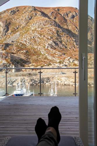 a person is looking out a window at a mountain at Gjermesøy Luxury Apartment in Ballstad