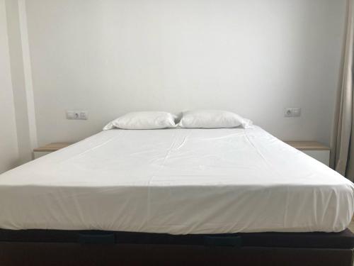 Una cama blanca con dos almohadas encima. en Shore View II Las Canteras by Canary365 en Las Palmas de Gran Canaria