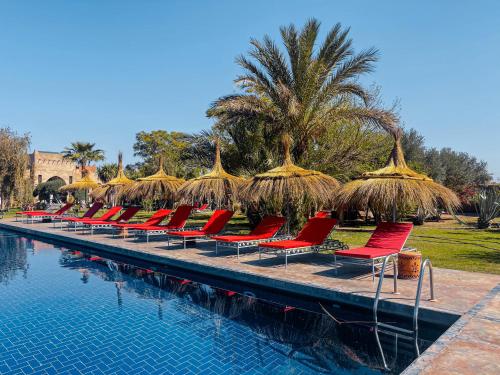 una fila de sillas con sombrillas de paja junto a una piscina en LE BLED DE GRE, en Marrakech